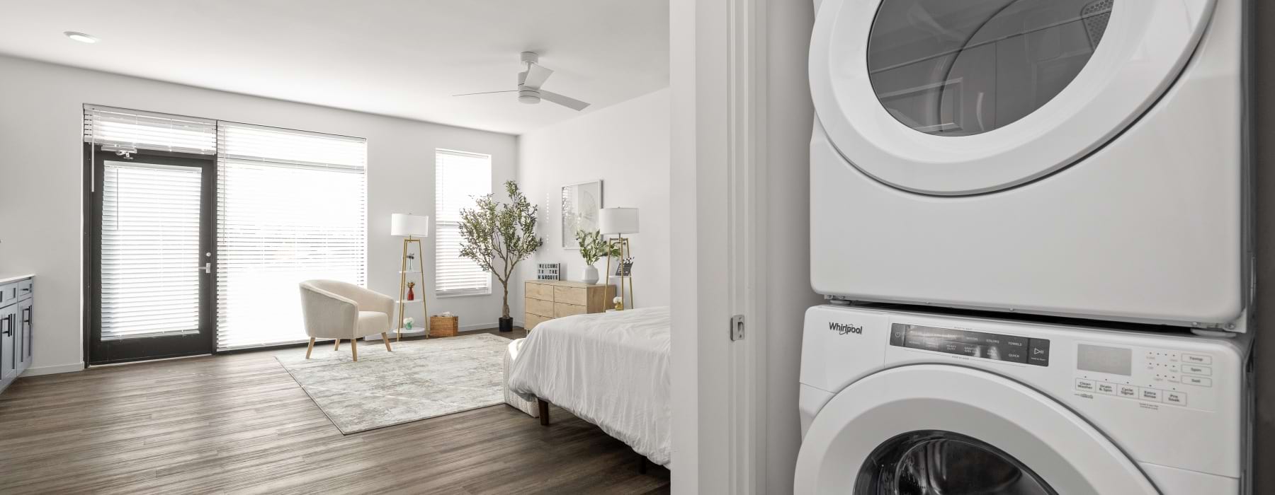 stacked washer and dryer in a closet with open concept studio floorplan expanding in background