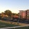 a football field with a few people and a rendered apartment building in the background
